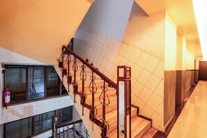 A multi-level interior with a staircase, tiled walls, and a fire extinguisher. - Fabhotel Bob'S (Patna)