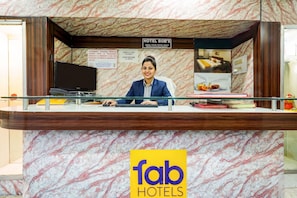 A hotel reception desk with a marble-patterned counter, a sign for Hotel Bob's, and a logo for Fab Hotels. - Fabhotel Bobs - 400m from Patna railway Station (Patna)