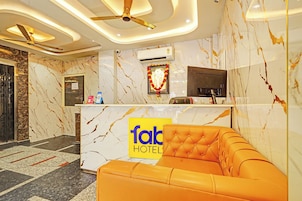 Ein Hotel-Empfangsbereich mit Marmorwand, einer Rezeption, einer Couch und einem Deckenventilator.