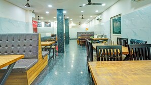 Un interior de restaurante con paredes de mármol, varios ventiladores de techo y diferentes opciones de asientos, incluyendo cabinas y mesas.