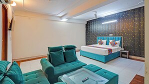 Quarto de hotel moderno com cama, sofá, mesa de centro e parede estampada.