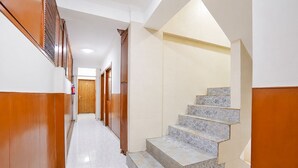 Um corredor com painéis de madeira, escada revestida de azulejos e um extintor de incêndio.