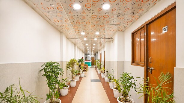 Um corredor com vasos de plantas, uma porta de madeira e teto com desenhos circulares.