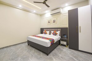 A bedroom with a bed, a wardrobe, a nightstand, and an air conditioning unit.