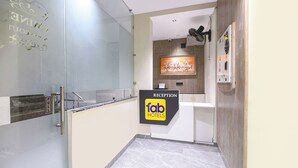 Ett väntrum med en glasvägg, en receptionsdisk, en väggmonterad luftkonditioneringsanläggning och en målning av hästar.