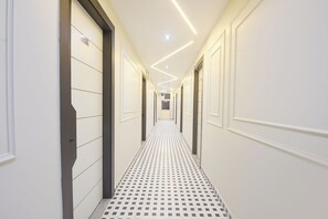 A hallway with a patterned floor, white walls, and a ceiling with recessed lighting.