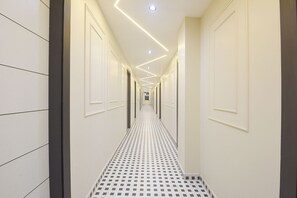 A hallway with patterned flooring, recessed ceiling lighting, and doors on both sides. - FabHotel Eminence Grand (New Delhi)