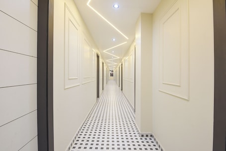 A hallway with patterned flooring, recessed ceiling lighting, and doors on both sides.. FabHotel Eminence Grand