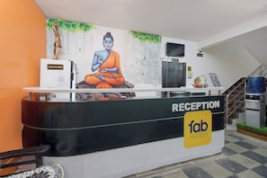 Uma receção com um mural de Buda, uma televisão e um sinal para Fab Hotels.