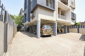A multi-story residential building with a covered parking area, a motorcycle, and a bicycle. - Fabhotel Himalay Guest House (Pune)