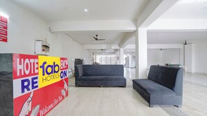 A hotel lobby with a reception desk, sofas, and a high ceiling with exposed beams. - Fabhotel Hr Residency (New Delhi)