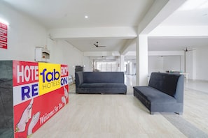 A hotel lobby with a reception desk, sofas, and a high ceiling with exposed beams. - Fabhotel Hr Residency (New Delhi)