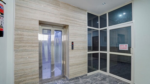 An elevator with a digital display, a glass door entrance, and a sign indicating a hotel-hospital residency. - Fabhotel Hr Residency (New Delhi)