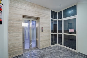 An elevator with a digital display, a glass door entrance, and a sign indicating a hotel-hospital residency. - Fabhotel Hr Residency (New Delhi)