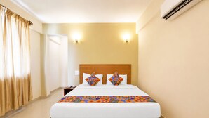 A hotel room with a wooden bed, two wall-mounted lights, and an air conditioning unit. - FabHotel Kartik Resort - 150M From Mandrem Beach (Mandrem)