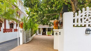 A pathway leading to a building with a white facade, a gated entrance with lion statues, and potted plants along the sides. - FabHotel Kartik Resort - 150M From Mandrem Beach (Mandrem)
