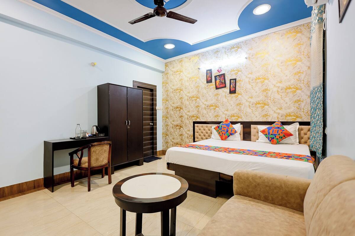 A hotel room with a bed, a desk, a chair, a round table, and a ceiling fan.