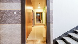 A hallway with wooden paneling, a tiled floor, and a staircase with marble steps. - Fabhotel Luxe Cozy (Varanasi)