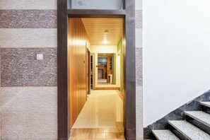 Un pasillo con paneles de madera, piso de baldosas y una escalera con escalones de mármol.
