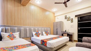 A hotel room with two beds, a desk, a chair, and a wardrobe. - Fabhotel Luxe Cozy (Varanasi)