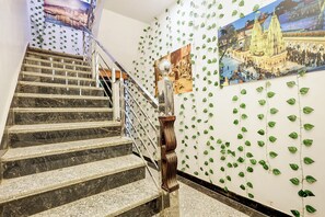 Una escalera con barandilla, una pared decorada con follaje verde y un cartel de un templo.