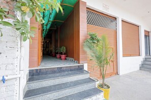 A building entrance with a tiled staircase, potted plants, and a wooden door. - Fabhotel Luxe Cozy (Varanasi)