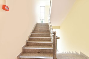 A staircase with granite steps and a metal handrail, leading to a door at the top.