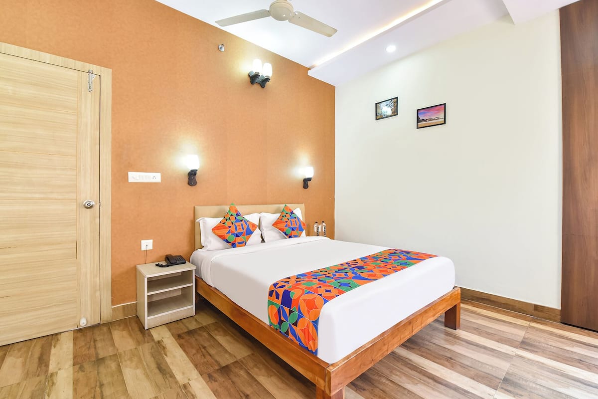 A hotel room with a wooden bed, a nightstand, a ceiling fan, and two wall-mounted lights.