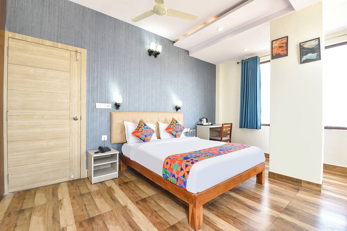 A hotel room with a bed, bedside table, desk, chair, and a wardrobe.