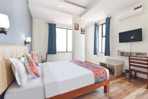 Ein Hotelzimmer mit einem Bett, einem Schreibtisch, einem Sessel, einem Fernseher und einer Klimaanlage.