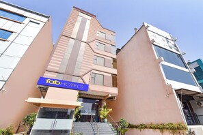 Et hotel med en moderne facade, et tydeligt blå skilt og en trappe, der fører til indgangen.