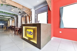 Ein Hotel-Empfangsbereich mit modernem Design, einer Rezeption und einem Essbereich im Hintergrund.