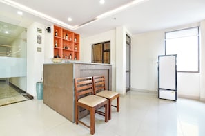 A clean, modern room with a wooden bench, a glass cabinet with bottles, and a large window.