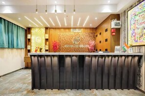 A hotel reception desk with a modern design, a clock, and a decorative wall. - Fabhotel Mh Grand (Kalol)