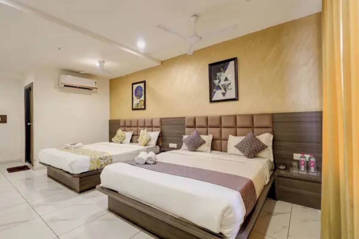 Habitación de hotel con dos camas, ventilador de techo, aire acondicionado y obras de arte en las paredes.