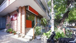 Um edifício com fachada de tijolos, entrada de vidro e uma scooter estacionada na frente.