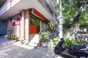 Un edificio con fachada de ladrillo, entrada de vidrio y una moto estacionada afuera.