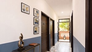 A hallway with a door marked '102', a wall-mounted sculpture, and framed pictures.
