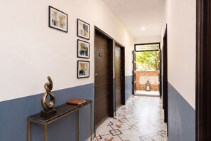 A hallway with a door marked '102', a wall-mounted sculpture, and framed pictures. - Fabhotel Mohan Villa (New Delhi)