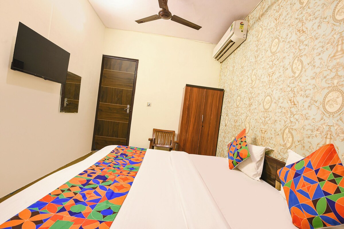 A bedroom with a bed, a chair, a wardrobe, a ceiling fan, and an air conditioning unit.