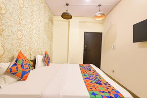 Una habitación de hotel con cama, papel tapiz estampado, una puerta y televisión en la pared.