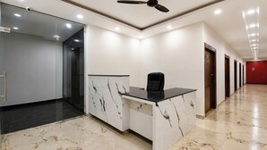 Ein moderner Arbeitsbereich mit Empfangstresen, Deckenventilator und einem Flur mit Türen.