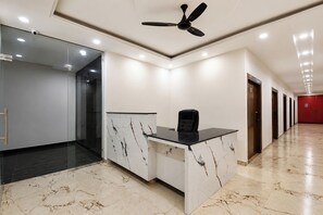 Un espacio de oficina moderno con un mostrador de recepción, un ventilador de techo y un pasillo con puertas.