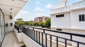 Ein Balkon mit schwarzem Geländer, einem klaren Himmel und Gebäuden im Hintergrund.