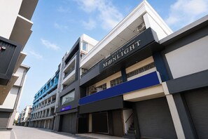 Un hotel modern amb un cartell ben visible de 'Moonlight', múltiples balcons i una façana neta i contemporània.