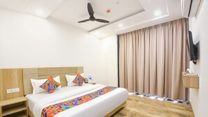 Ein Hotelzimmer mit Bett, Deckenventilator, Fernseher und einem Fenster mit Vorhängen.