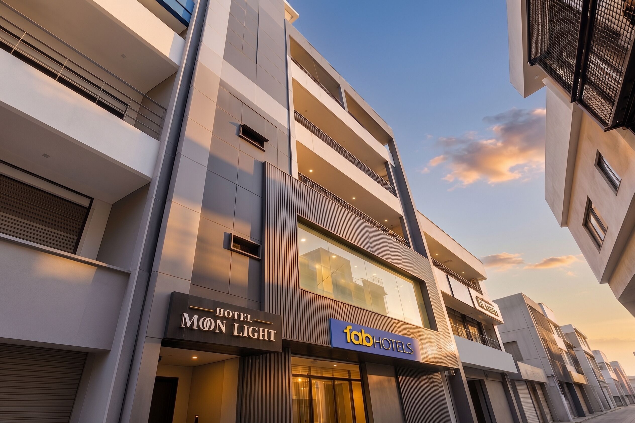 A modern hotel building with a sign for 'Mon Light' and 'Fab Hotels.'