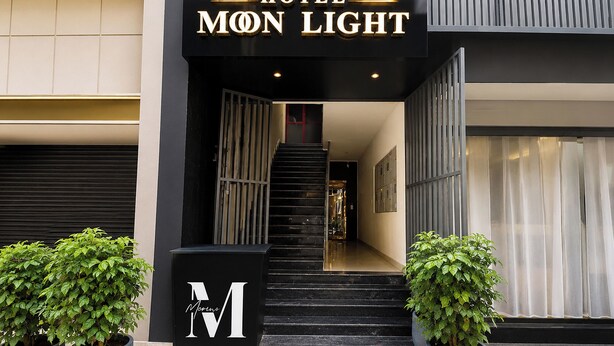 Der Eingang zum Hotel Mon Light mit einer Treppe zum Empfangsbereich, Blumentöpfen und einer modernen Fassade.