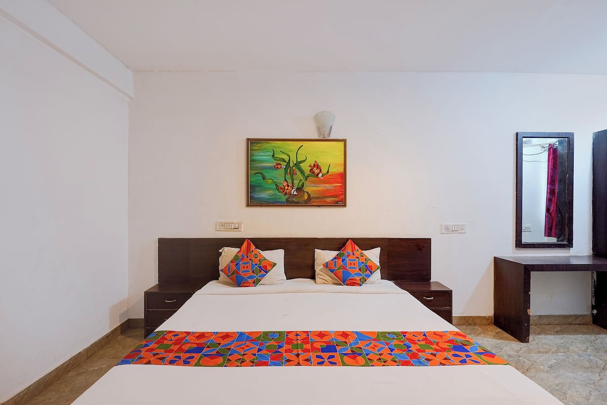 A hotel room with a bed, two nightstands, a painting, and a mirror.