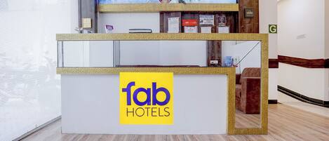 A hotel reception desk with a 'fab hotels' sign, a digital screen displaying a cityscape, and a 'G' sign indicating the ground floor.